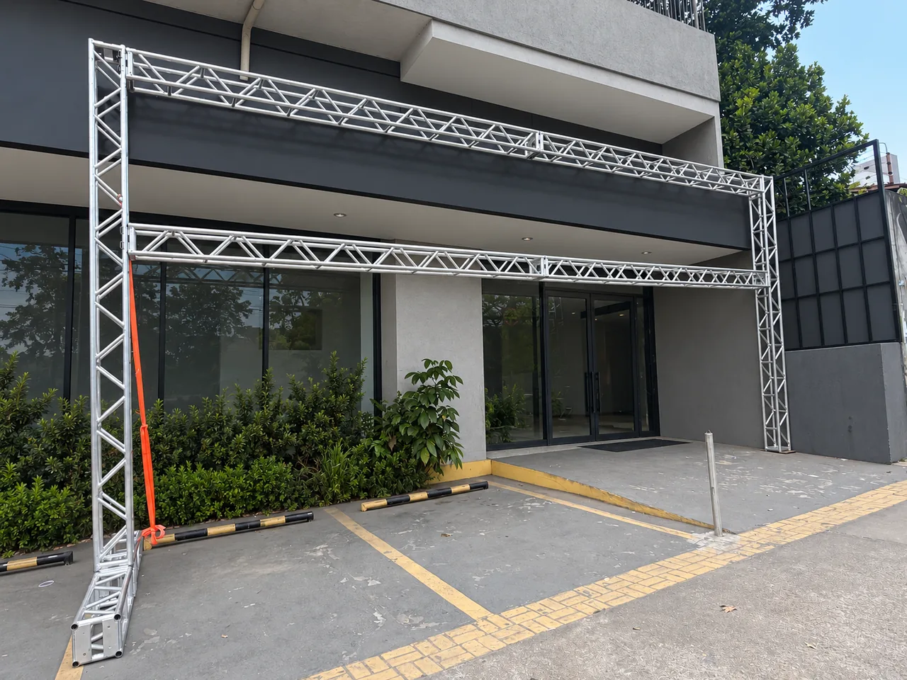 Portal de treliça metálica montado em área externa, com fundo editado para remover a identificação do local